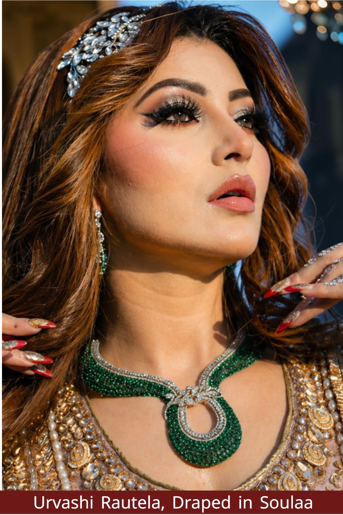 Urvashi Rautela wearing a green and silver necklace with a blurred background